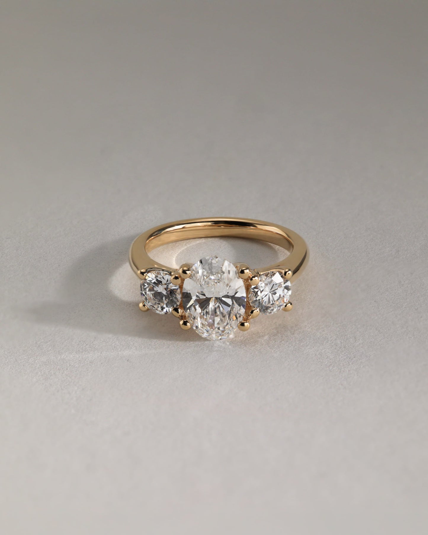 Grace - Oval Claw Trilogy with Round Side Stones, Open Trellis Gallery and Tapered Band Engagement Ring - Rose Gold