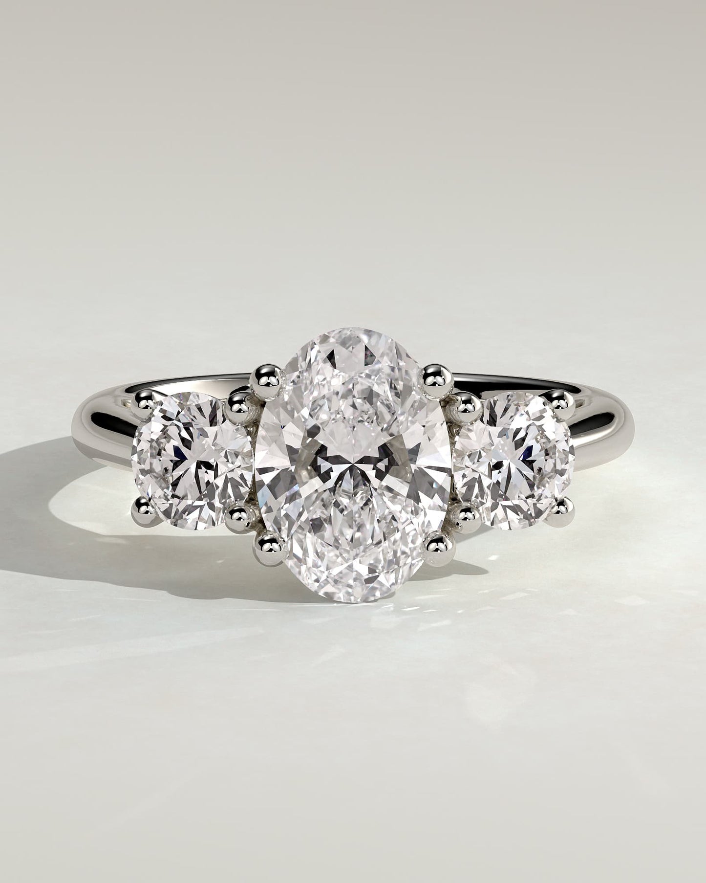 Grace - Oval Claw Trilogy with Round Side Stones, Open Trellis Gallery and Tapered Band Engagement Ring - White Gold