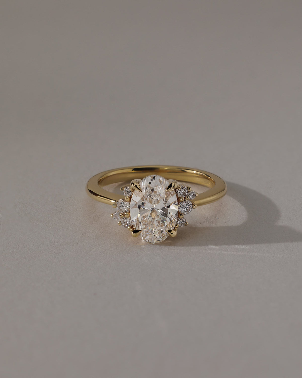 Esther - Oval Claw Solitaire with Clustered Round Opposing Shoulder Stones Engagement Ring - Yellow Gold