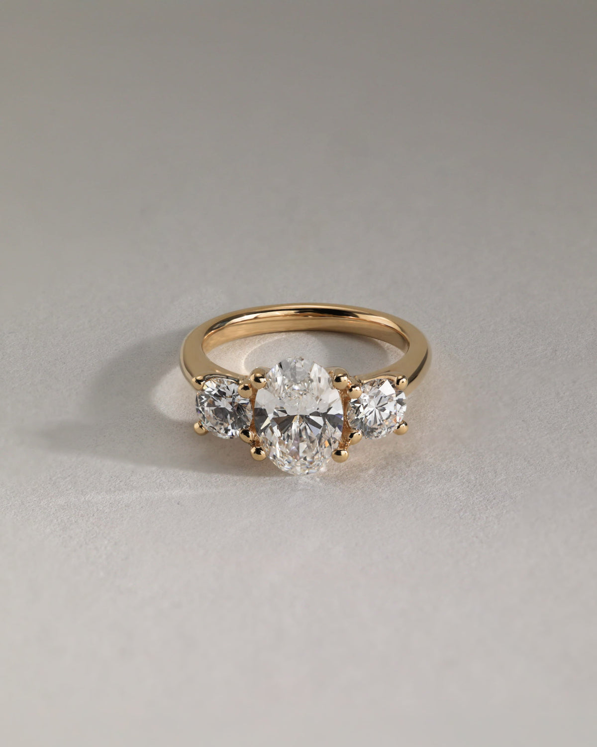 Grace - Oval Claw Trilogy with Round Side Stones, Open Trellis Gallery and Tapered Band Engagement Ring - Yellow Gold