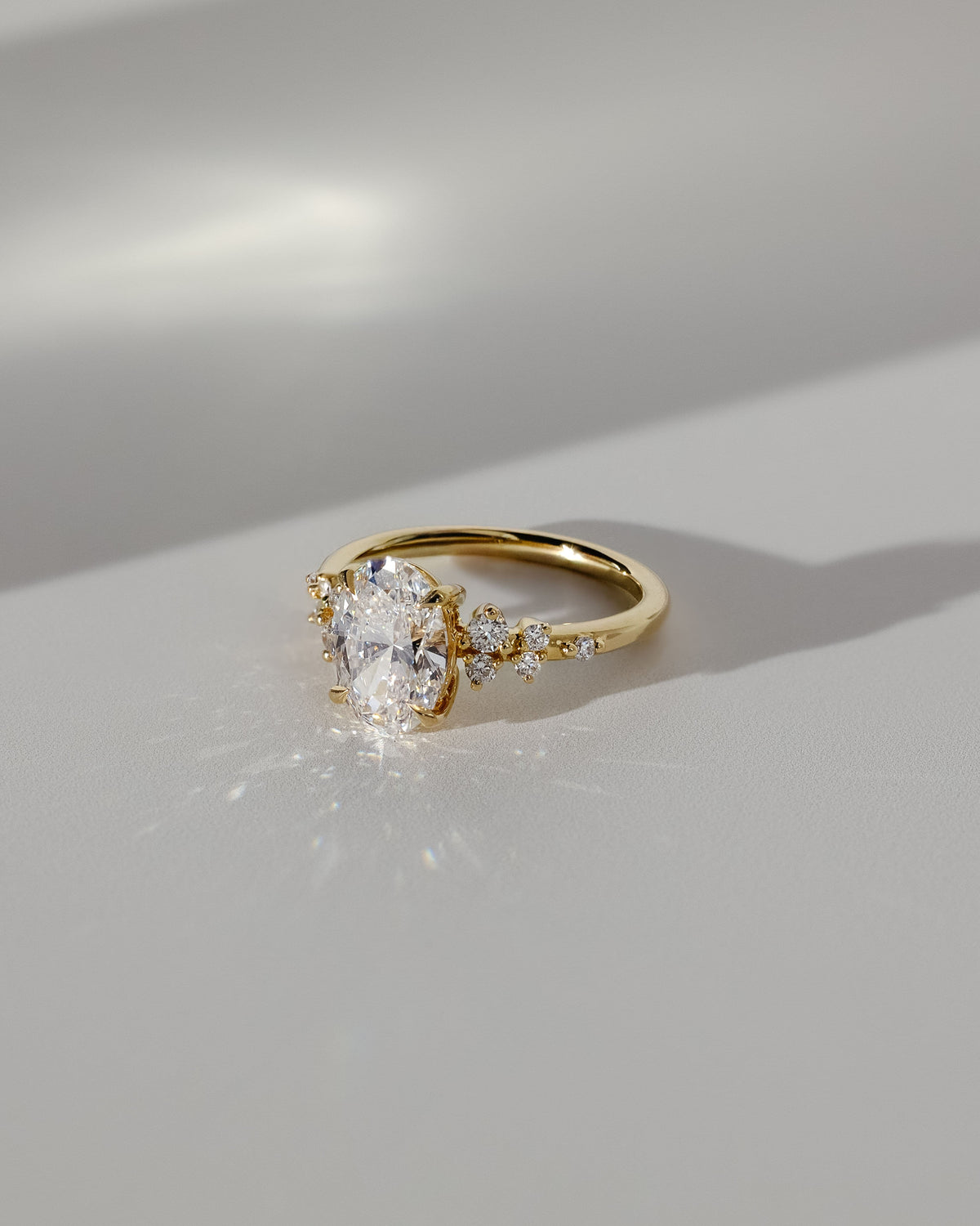Bella - Oval Claw Solitaire with Clustered Round Shoulder Stones Engagement Ring - Yellow Gold
